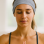 Woman meditating with eyes closed wearing a gray headband and black tank top.